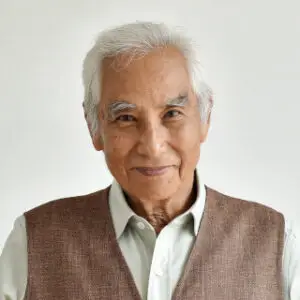 Older Asian man wearing a brown vest with a smile.