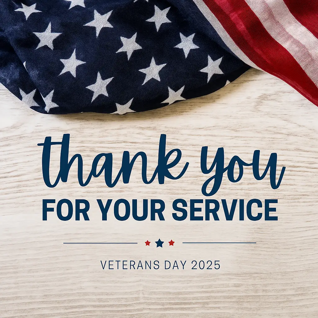 An American flag draped across the top of a light wooden background with navy text reading ‘thank you FOR YOUR SERVICE’ and smaller text below that says ‘Veterans Day 2025,’ accented by small red and blue stars.