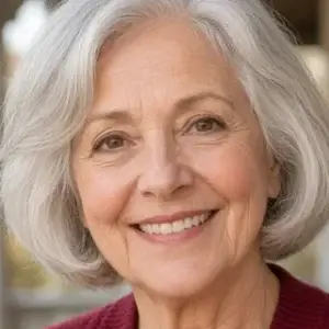 Smiling older woman with silver hair in a cranberry cardigan on a porch